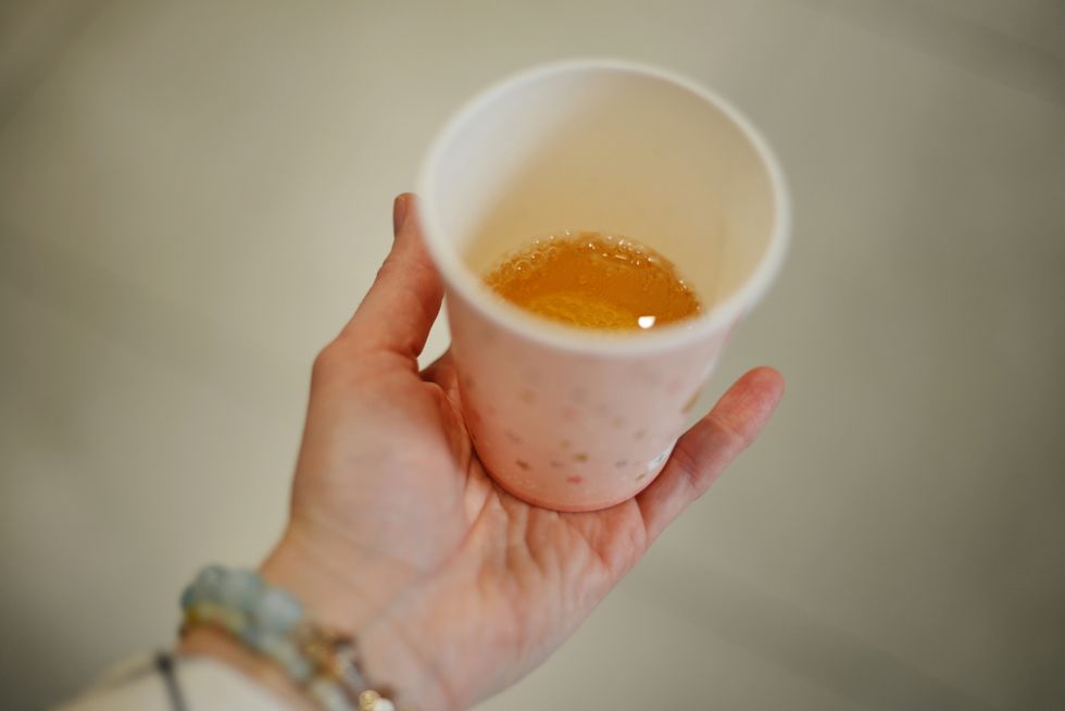 a person holding a cup of urine, for a drug test