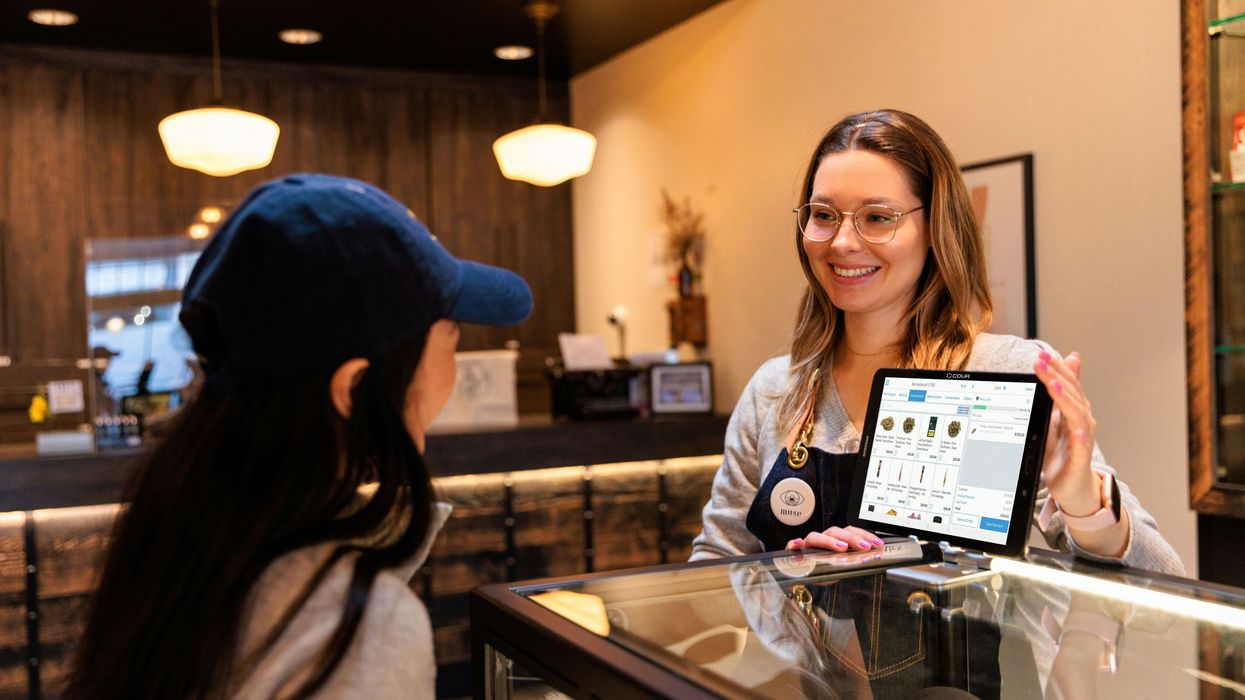 a woman showing a tablet to another woman at a cannabis dispensary