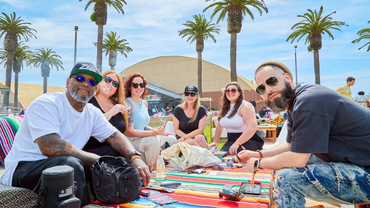Diverse mix of people sitting outdoors, around a table smiling at camera