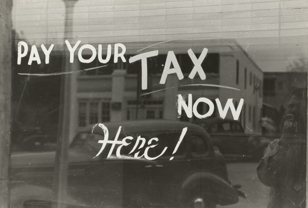 historical image of store window that says - "pay your taxes now, here!" 