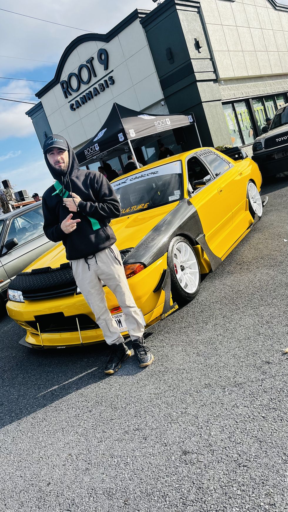 image from Root 9 Dispensary's Cars & Coffee event featuring exotic and classic cars outside it's retail location