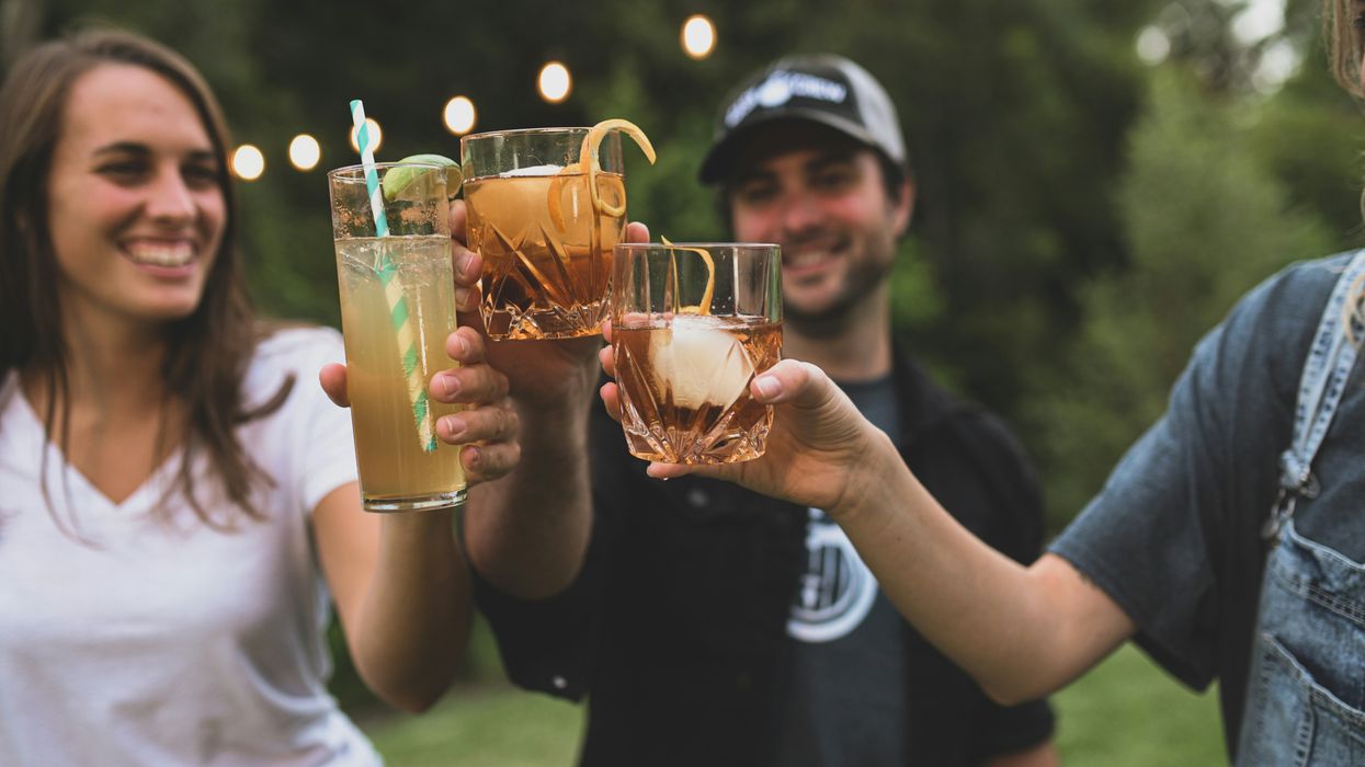 image of friends holding drinks with alcohol, clinking glasses to cheers
