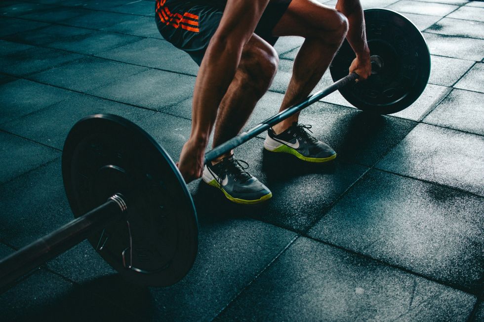 partial image of person about to deadlift a barbell off the ground